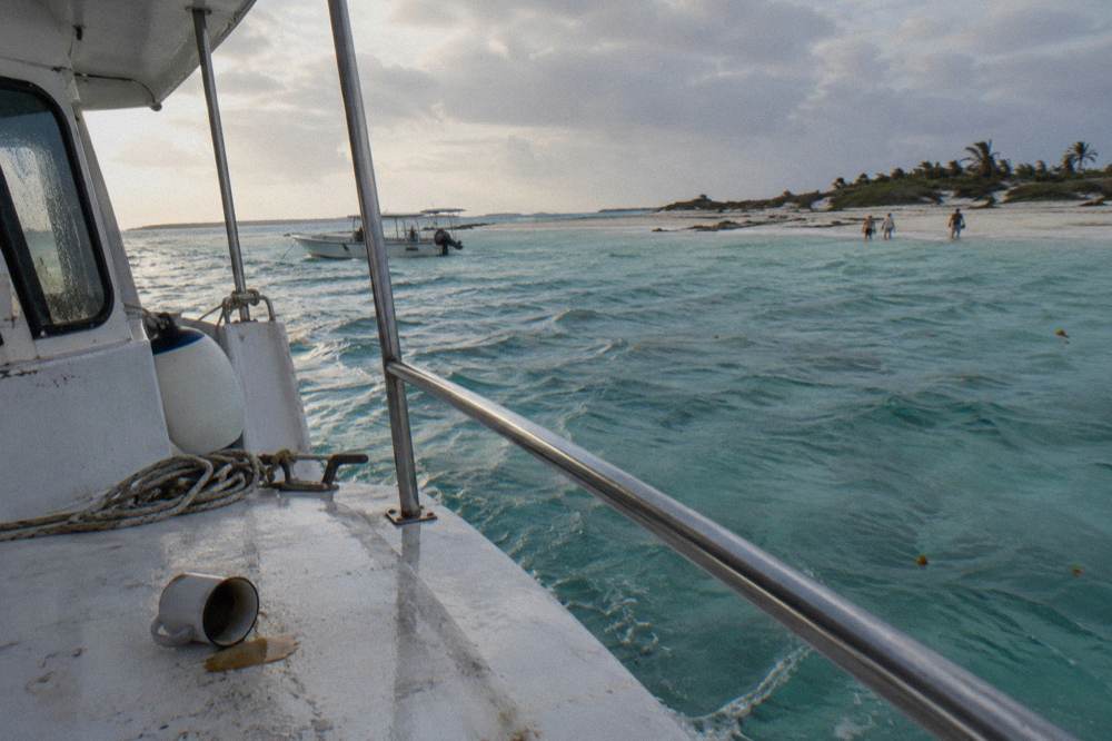 A tour boat anchored beside a shallow sandbar on a calm clear morning