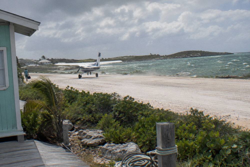 A small island airstrip of pale coral rock beside turquoise sea