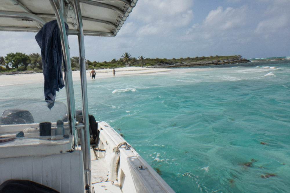 A tour boat anchored beside a sandbar in shallow turquoise water
