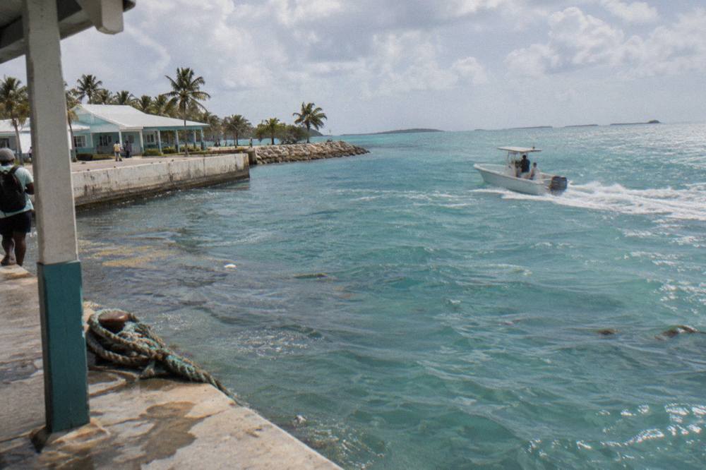 An open bow powerboat at speed on calm turquoise water with distant cays on the horizon