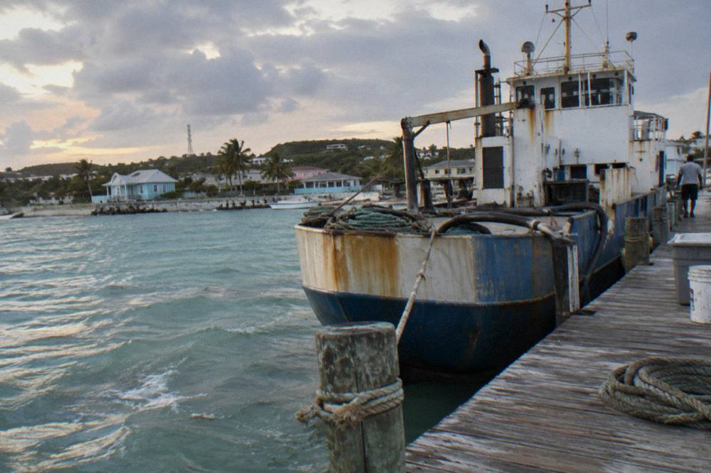A weathered cargo mail boat moored at a dock beside calm island water