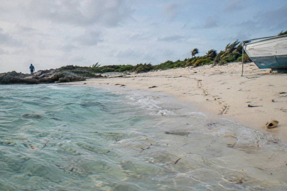 Clear shallow water over a white sand bottom with a distant uninhabited cay lined with low vegetation