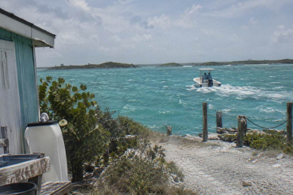 A small powerboat crossing wide open turquoise water toward a line of low green cays