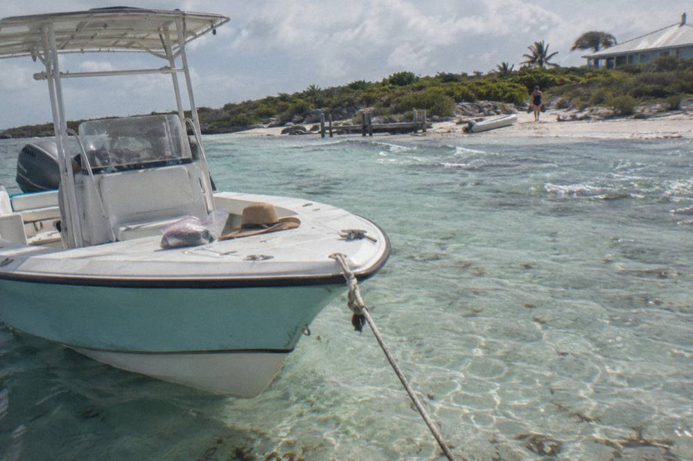 A powerboat moored beside clear shallow water at a small Exuma cay