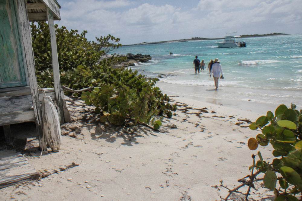 Tour guests walking up a white sand beach on a small Exuma cay