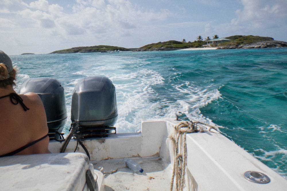 A powerboat cruising across open turquoise water toward small green cays