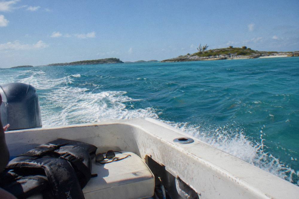 A speedboat crossing open turquoise water toward small rocky cays