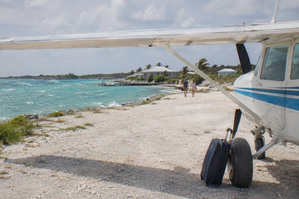 A light aircraft parked on a small grass airstrip beside turquoise water