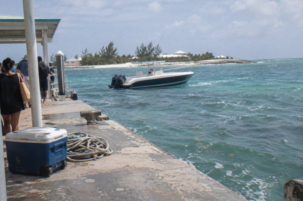 A speedboat anchored in clear shallow water beside a narrow strip of white sand