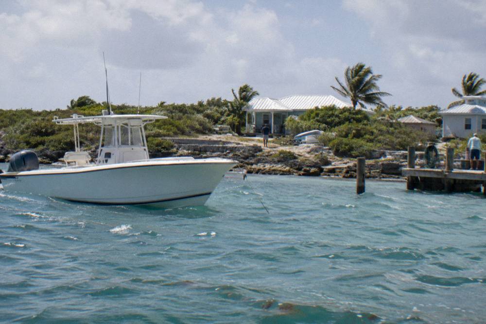 A white powerboat anchored near a small rocky island in turquoise water