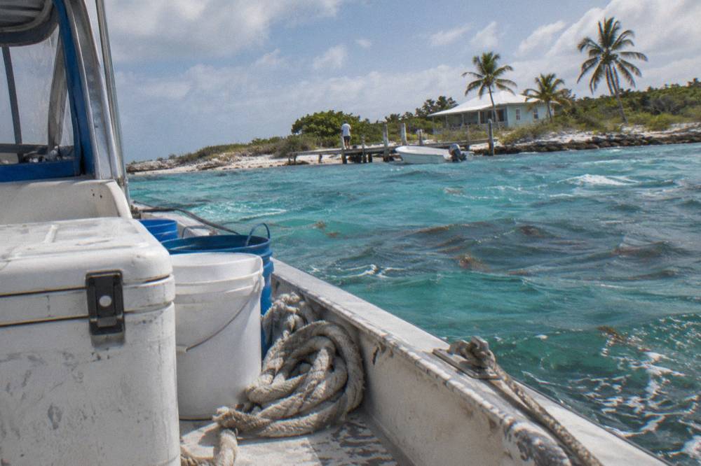 A boat deck with a covered cooler and crew equipment docked in calm turquoise water