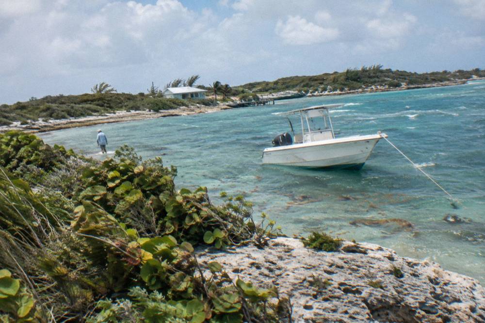 A powerboat anchored off a small scrubby cay in clear shallow water