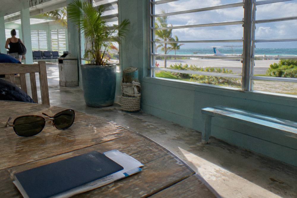 Open passport and boarding pass resting on a wooden table beside a pair of sunglasses