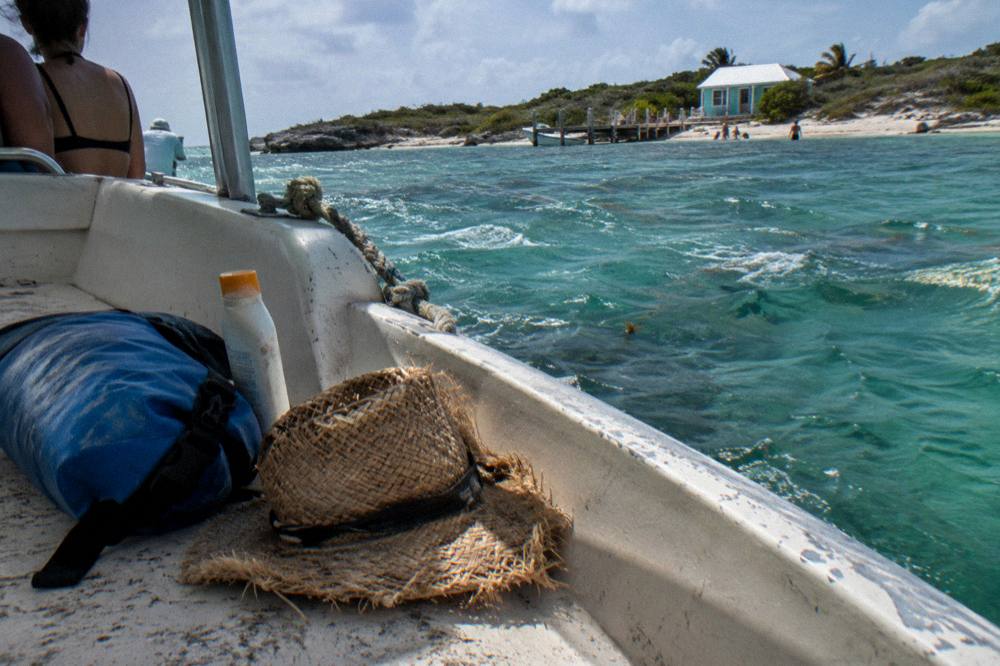 Dry bag, sunscreen and hat arranged on the bench seat of a boat