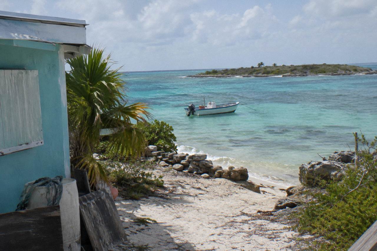 Turquoise shallows and a small boat anchored off a low Exuma cay