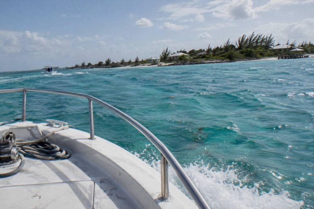 A powerboat cutting across open turquoise water toward a line of low cays