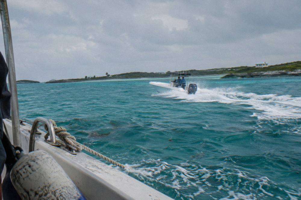 A powerboat cruising across open turquoise water toward a line of low cays