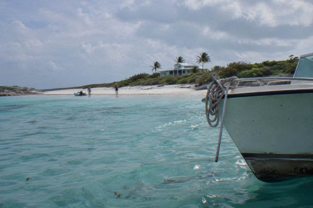 A boat anchored beside a white sandbar with calm shallow water
