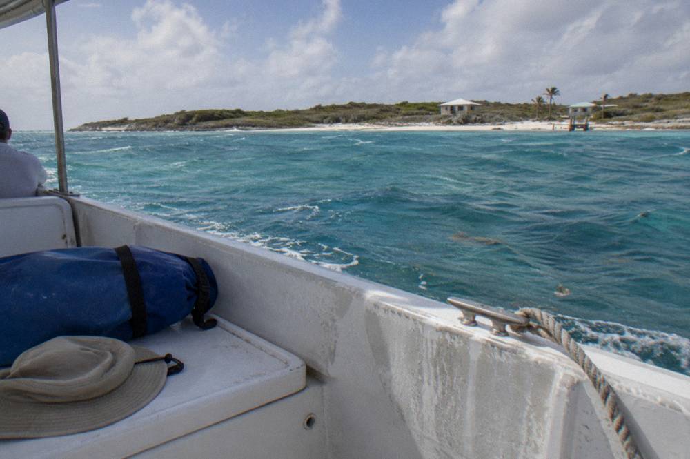 A dry bag and sun hat resting on a boat seat in bright sunlight