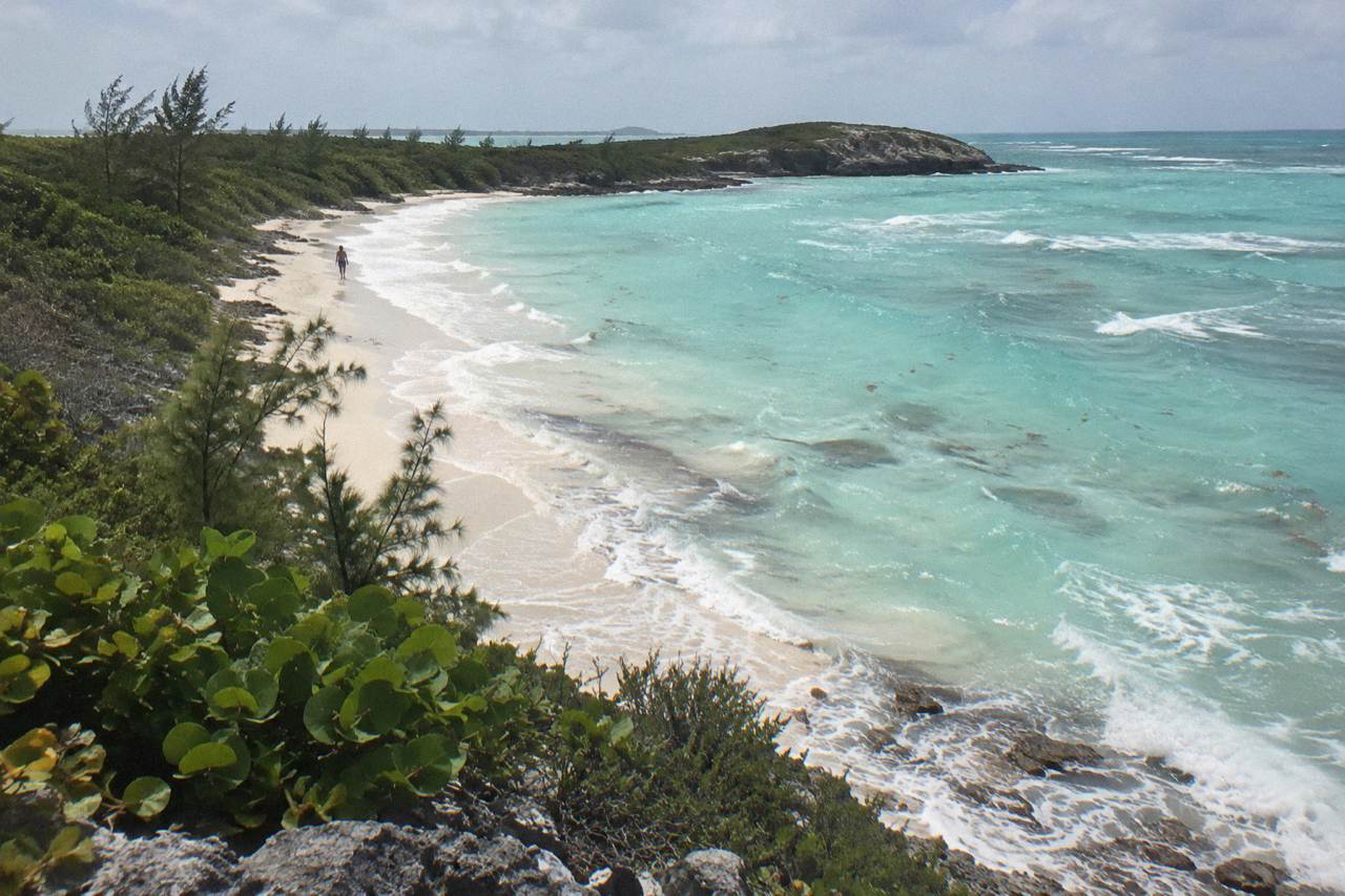 Turquoise shallow water lapping a small sandy beach on an uninhabited cay