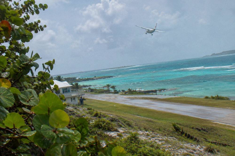 A light aircraft over turquoise island water near a small cay airstrip