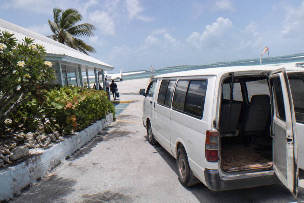 A taxi van parked outside a small airport terminal under a clear sky