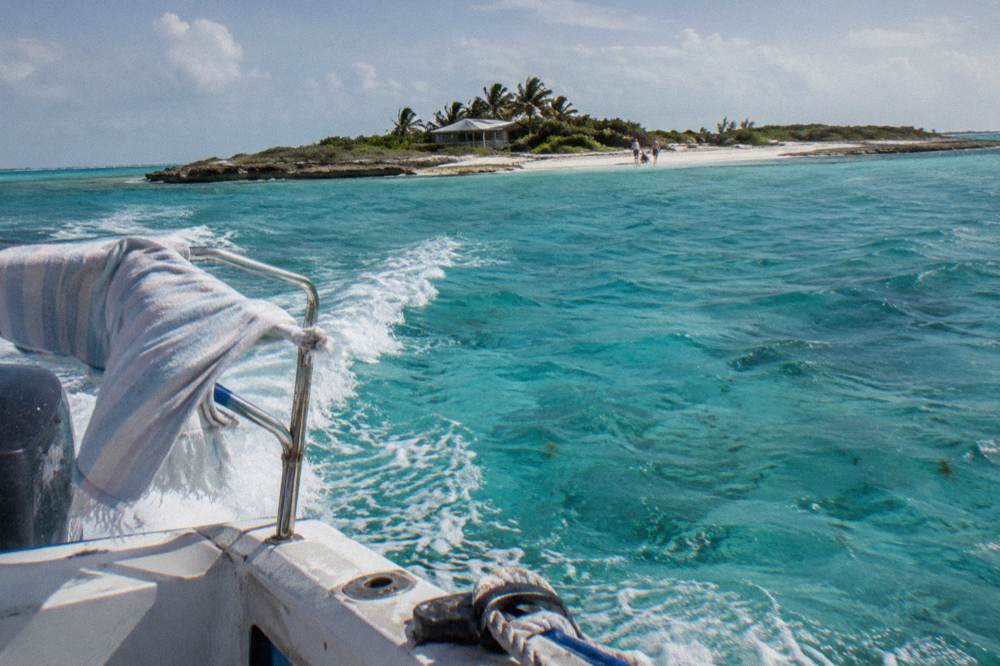 Speedboat cruising over clear turquoise water toward a small sandy island