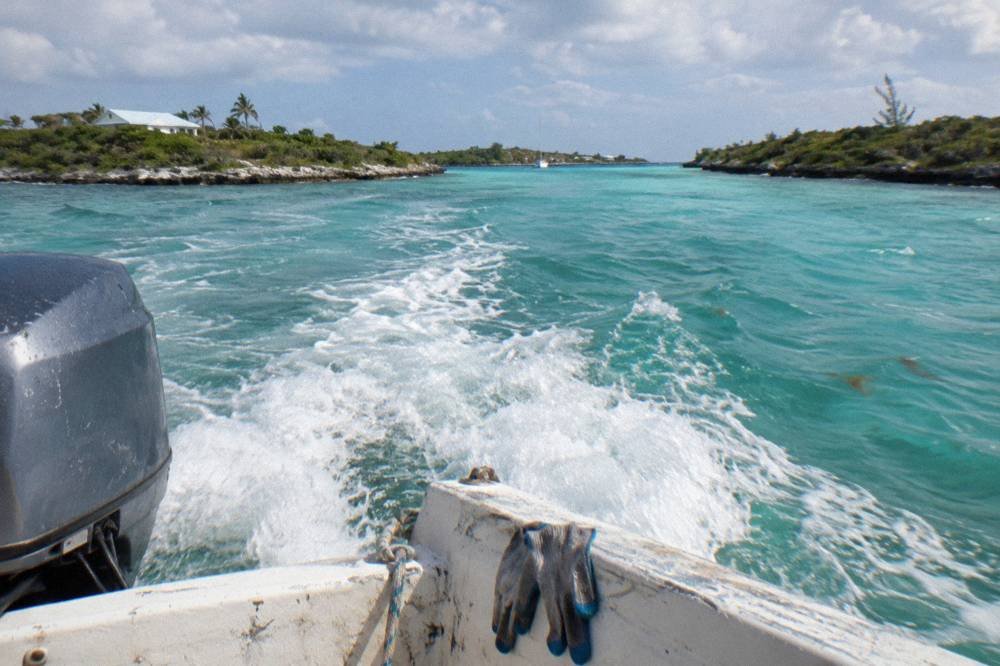 Turquoise channel water between two green cays seen from a moving boat