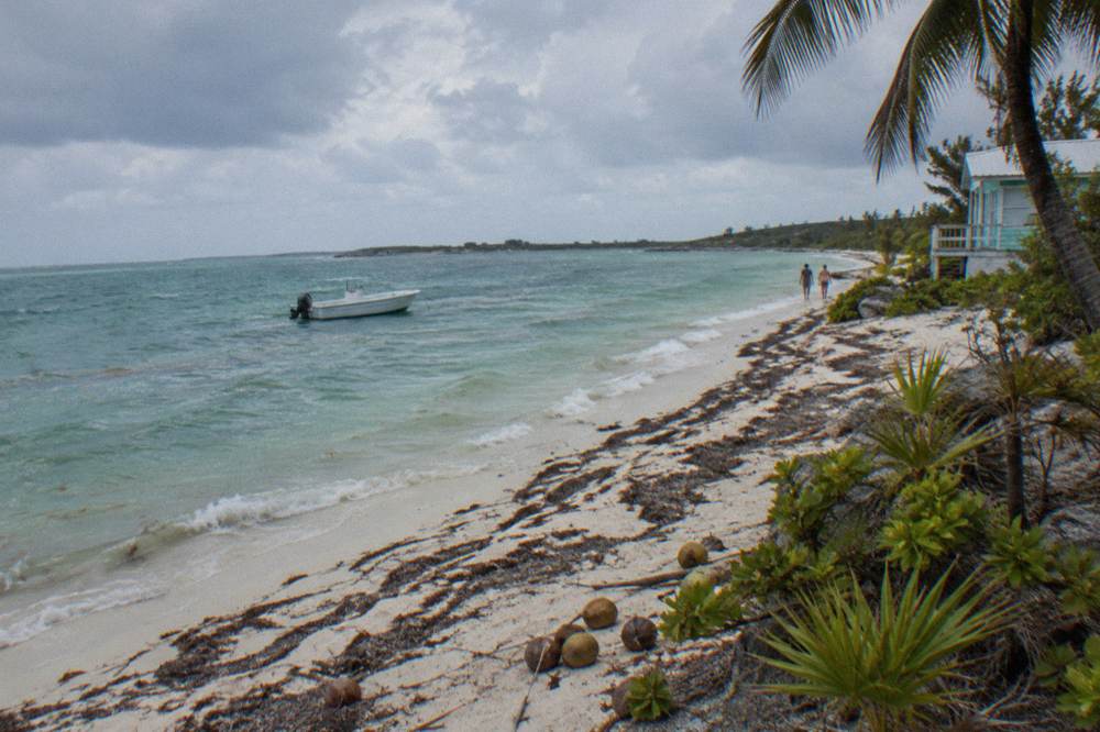 A small boat anchored near a sandbar with shallow clear water on all sides