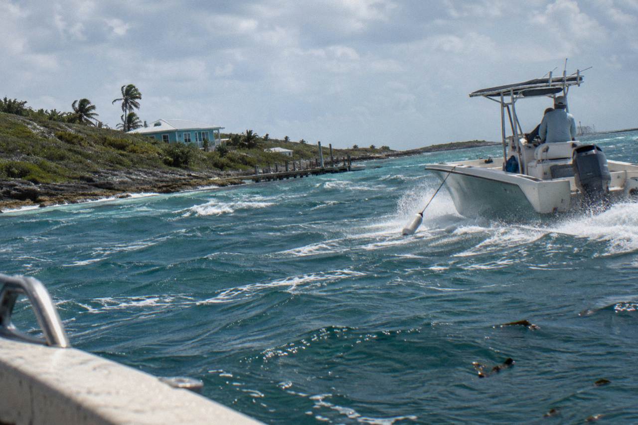A powerboat cutting across turquoise water between small Exuma cays