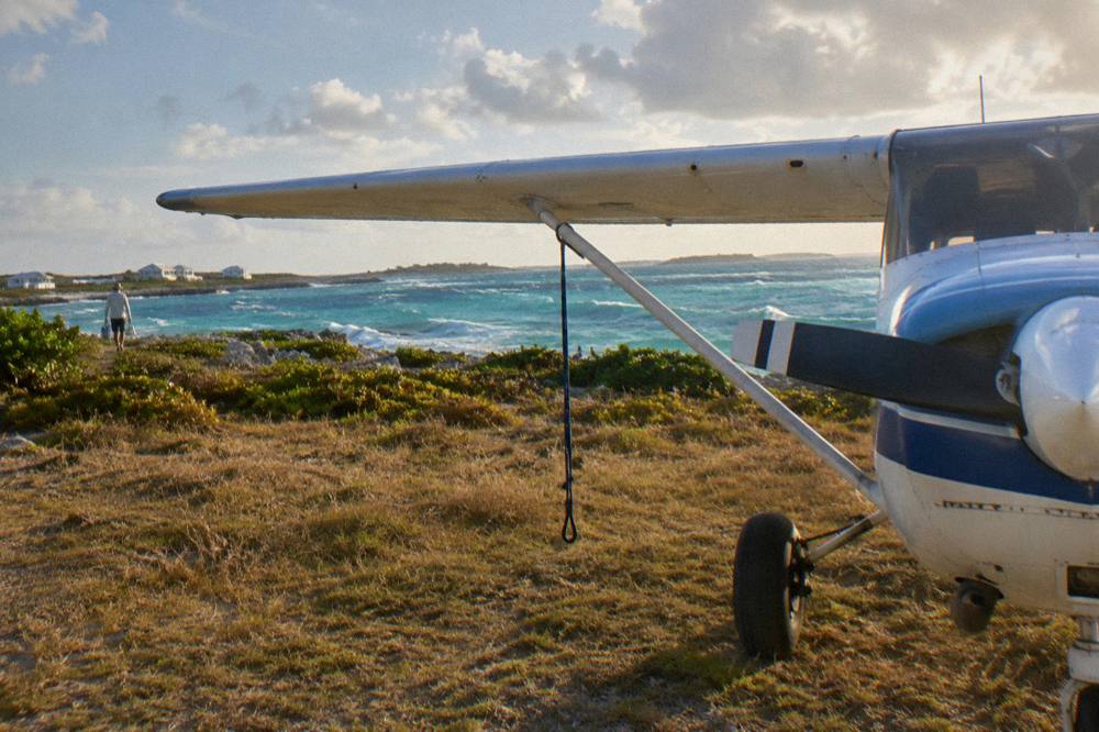Light aircraft parked on a small island airstrip beside turquoise water