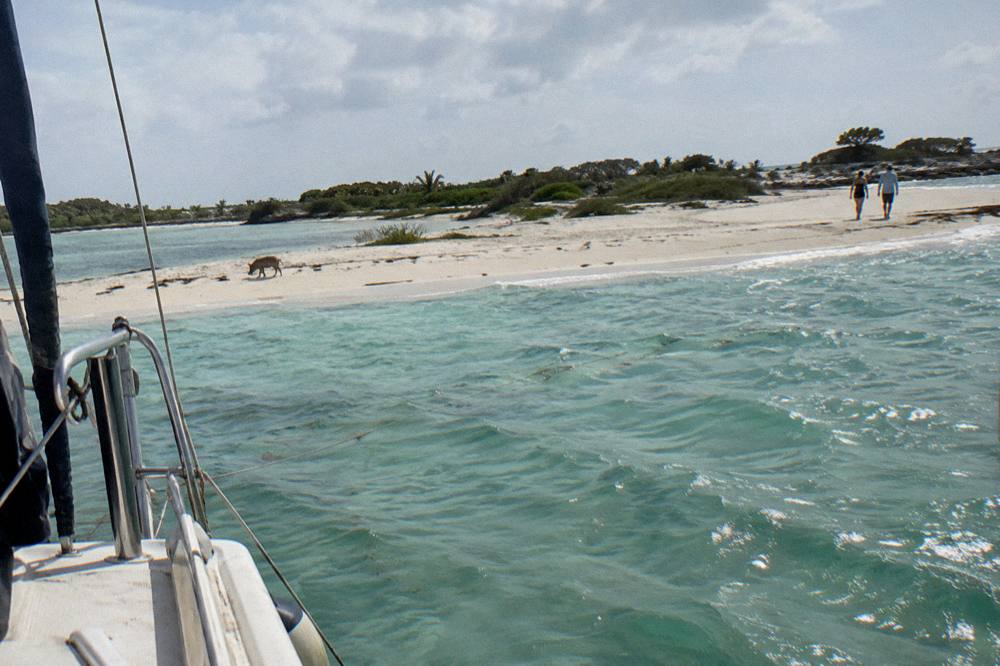 Boat anchored off a white sandbar with shallow clear water on both sides