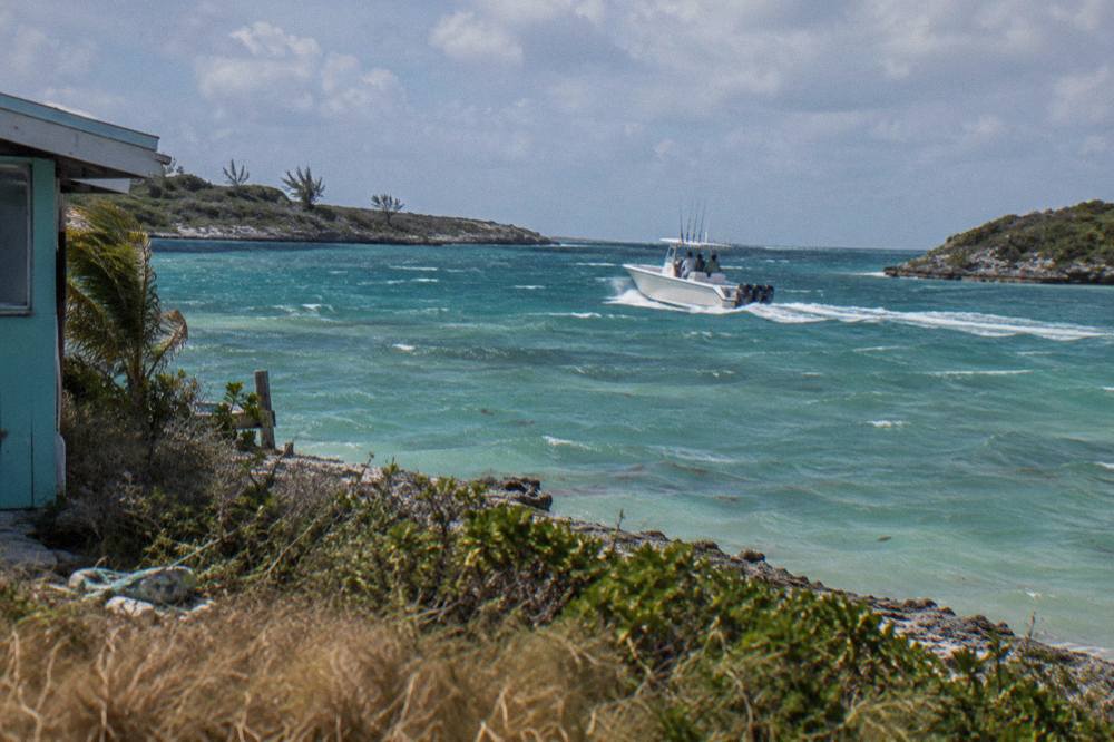 A charter boat crossing clear shallow water between two small cays