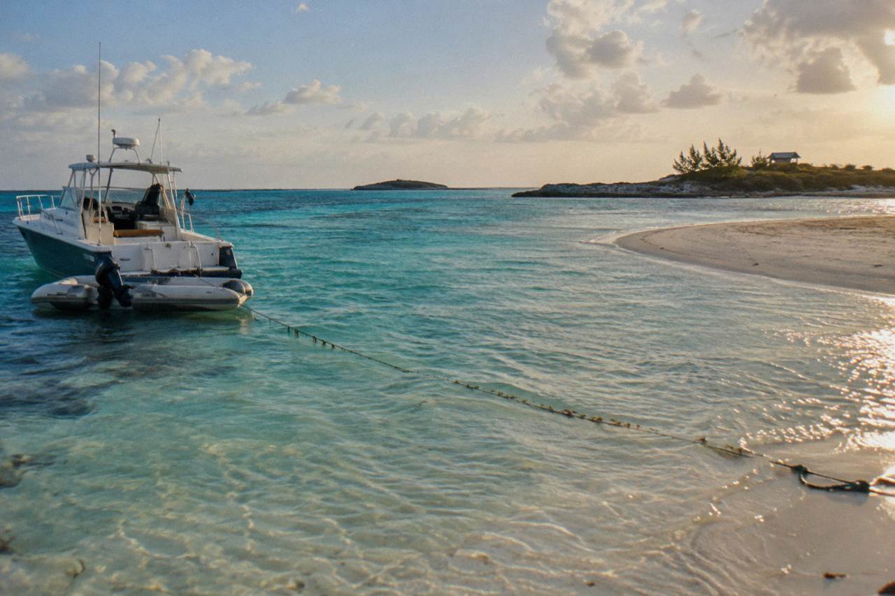 A private charter boat anchored beside a empty sandbar in shallow turquoise water