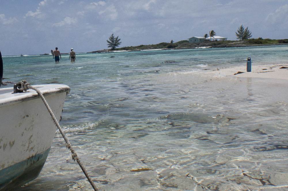 Visitors wading in shallow water along a bright sandbar