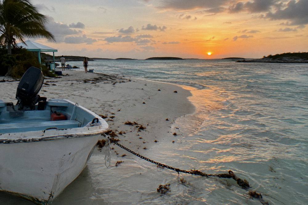 A calm sandbar at low tide surrounded by clear shallow water and small cays