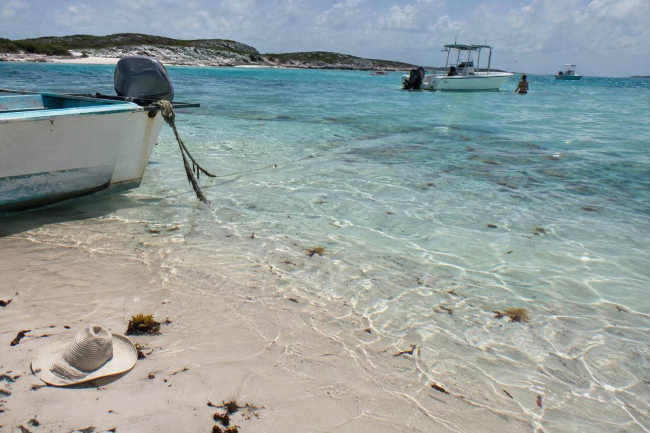 A wide sandbar rising from shallow turquoise water under a clear sky