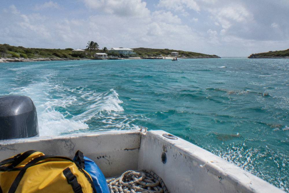 A powerboat cutting across open turquoise water toward small cays
