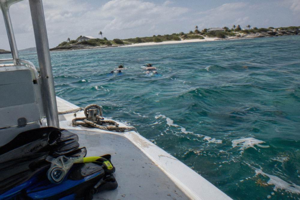 Snorkelers in the water beside a boat near a small reef