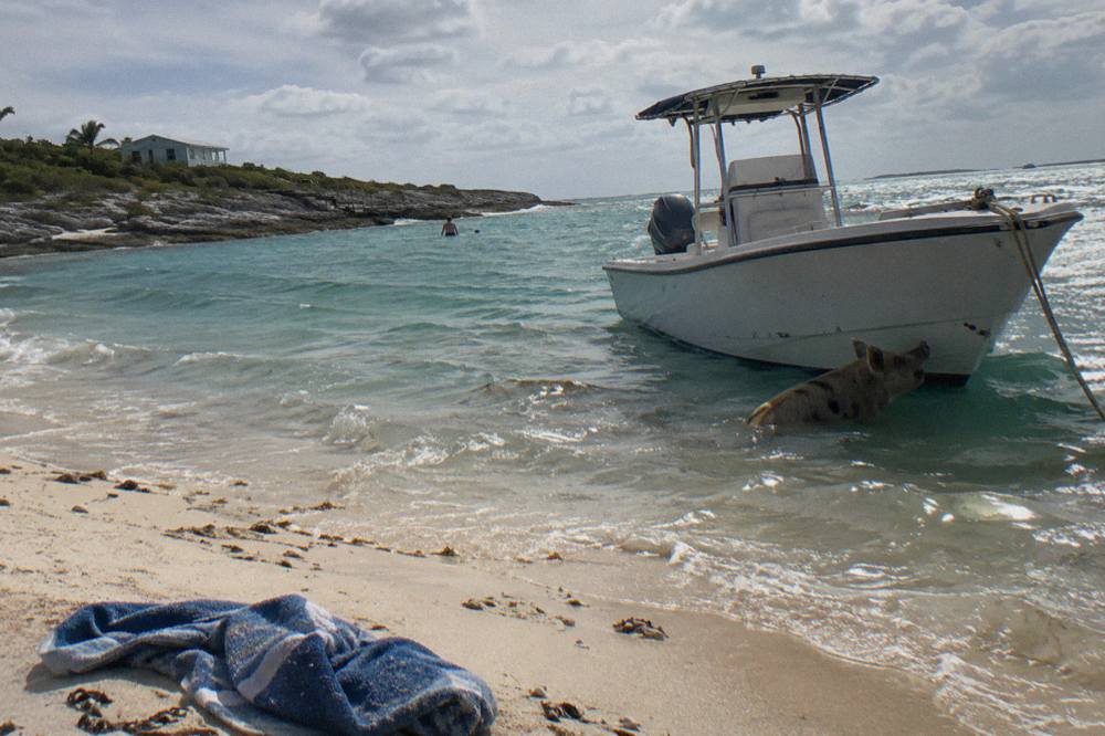 A speedboat anchored beside a small sandy cay in clear turquoise water