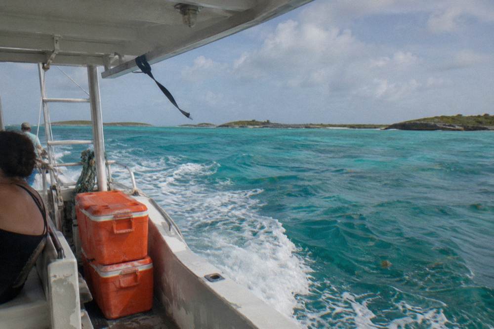 A tour boat cruising past low green cays on open turquoise water
