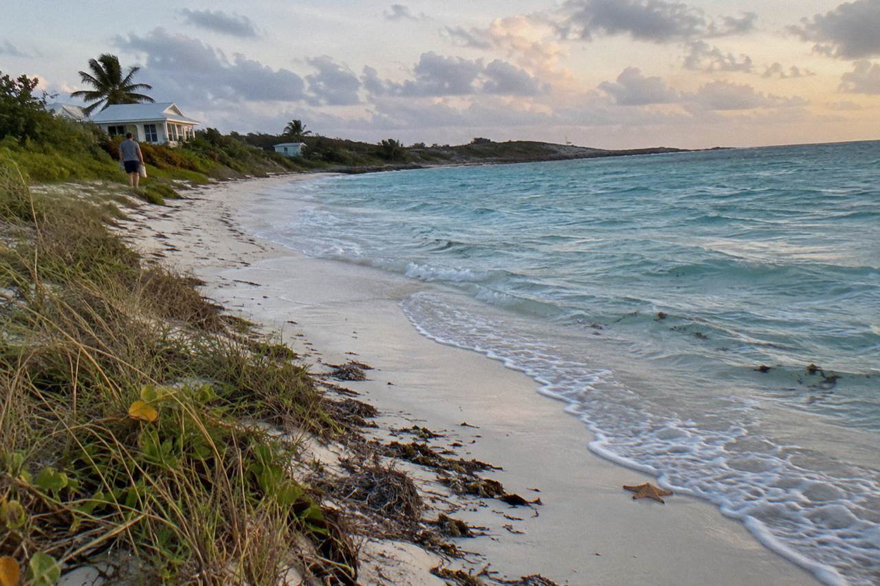 Empty white sand beach curving along turquoise water at Tropic of Cancer Beach on a calm morning
