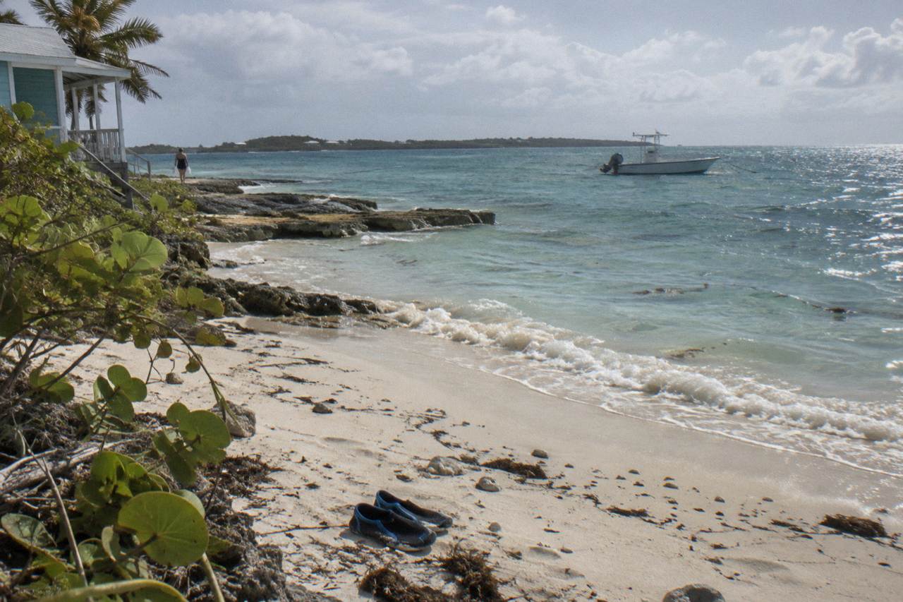 Turquoise shallow water at an Exuma beach with a small boat anchored offshore