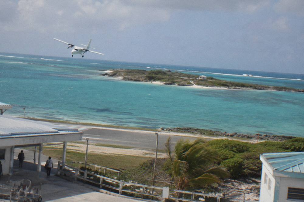 Light aircraft banking over turquoise Exuma shallows near a coral cay