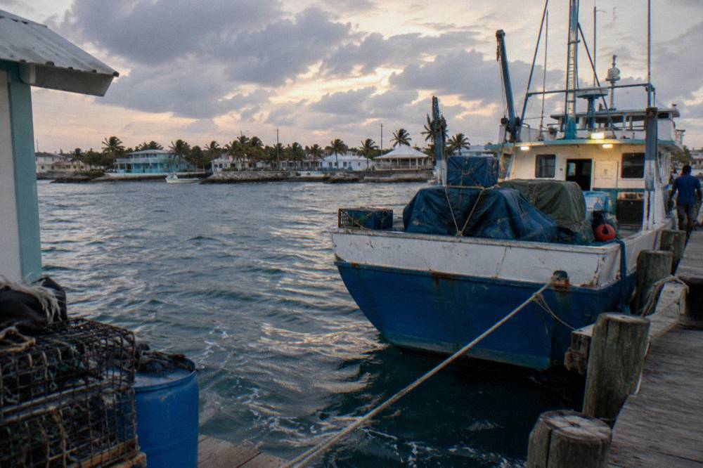 A Bahamian mail boat tied at a wooden dock at dusk