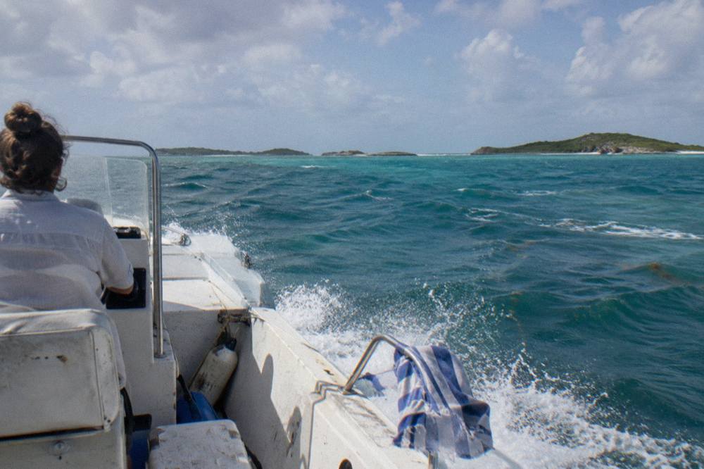 A powerboat cutting across open turquoise water toward low green cays on the horizon