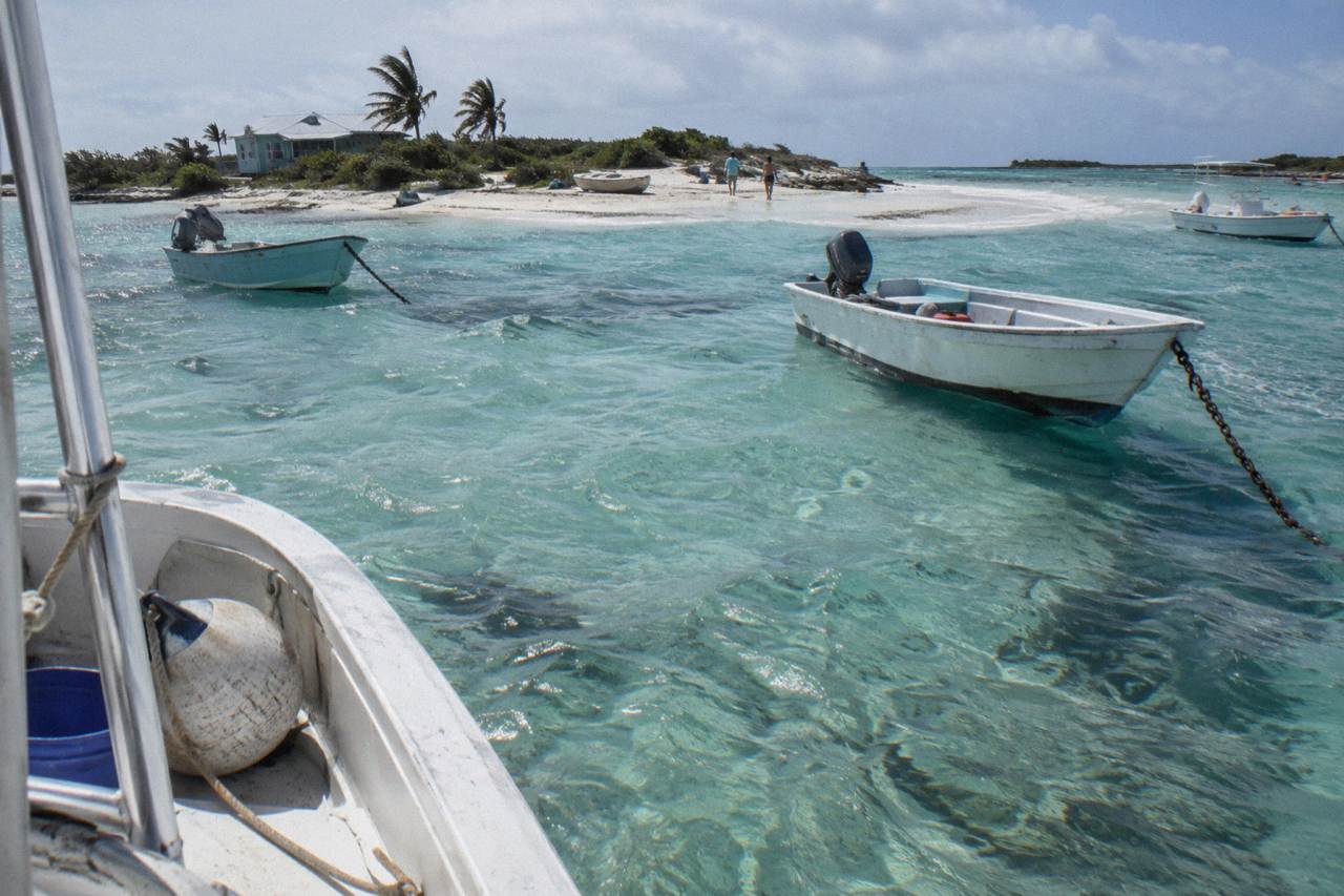Turquoise shallow water around a small Exuma cay with a white sandbar and moored boats