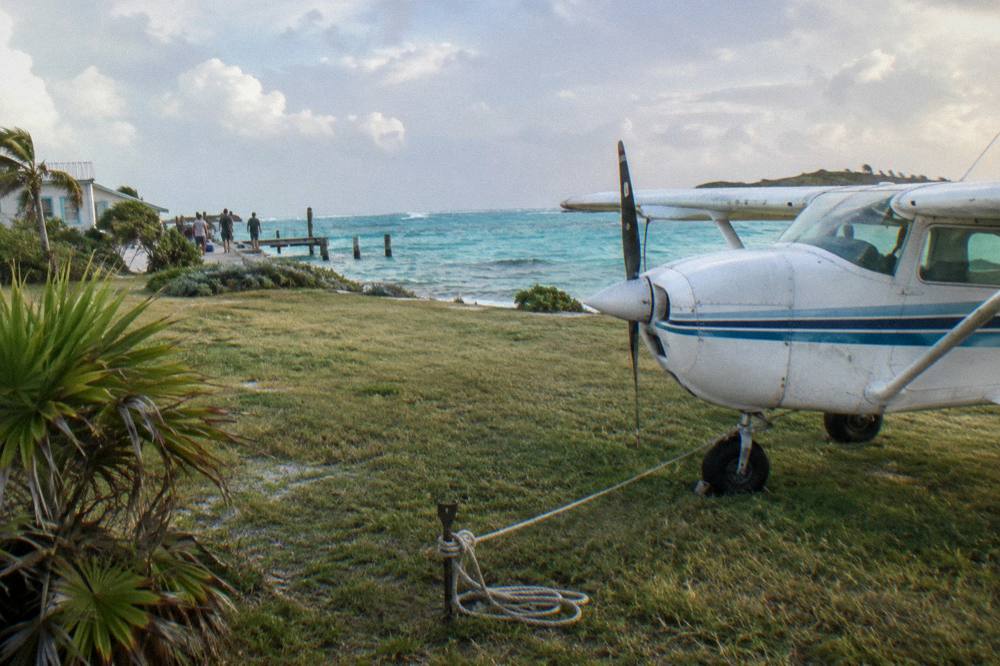 A light aircraft on a small island airstrip beside turquoise water
