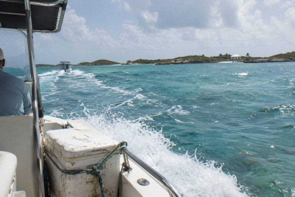 A powerboat cruising across open turquoise water toward small islands
