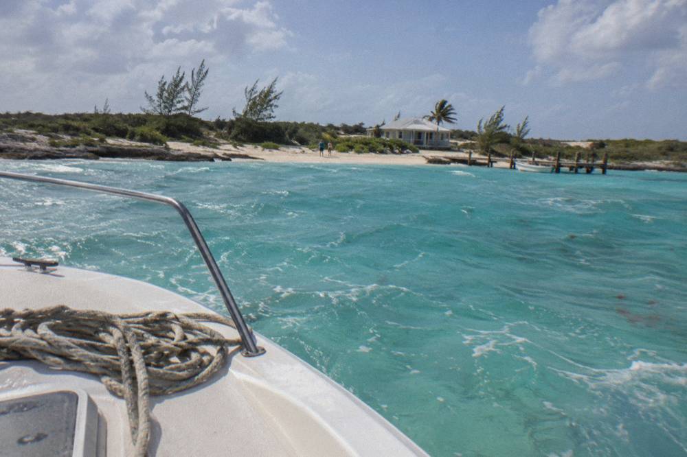 A boat anchored in shallow turquoise water beside a small sandy island